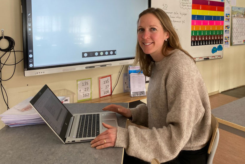 Kvinnlig lärare framför dator i klassrum